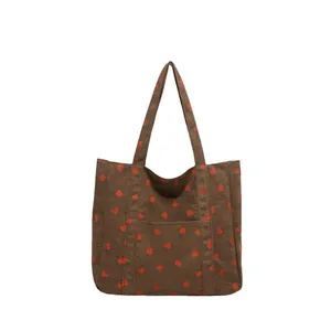 Brown corduroy tote bag with red strawberry print and a front pocket on white background