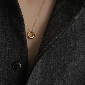 Minimalist gold hoop pendant necklace for women with polished finish on a grey suit jacket