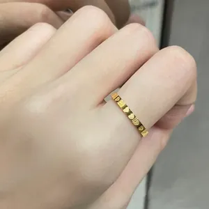 Minimalistischer vergoldeter Edelstahlring mit Herzmuster an der Hand des Models