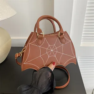 Brown bat-shaped leather handbag with white spider web embroidery and shoulder strap