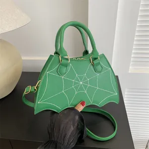 Green bat-shaped faux leather handbag with spider web stitching and crossbody strap