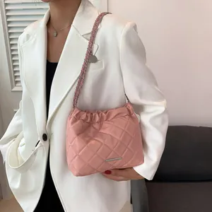 Rosafarbene gesteppte Schultertasche mit Silberkette, getragen von Model im weißen Anzug
