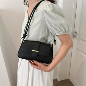 Sac à bandoulière noir minimaliste avec boucle en métal doré et détails de nœuds