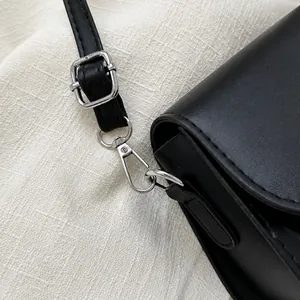 Detail van zilveren metalen sluiting en verstelbare riem op zwarte leren tas
