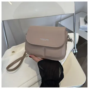 Detail van beige zadeltas met Fashion Trend tekst en rechthoekige reliëfstructuur
