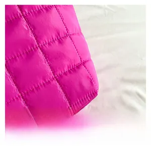 Makroaufnahme von pinkfarbenem, gestepptem Pufferstoff mit glänzender Textur und Nähten