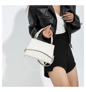 Détail d'un sac à main crème avec motif de pierre et poignée tressée sur un modèle