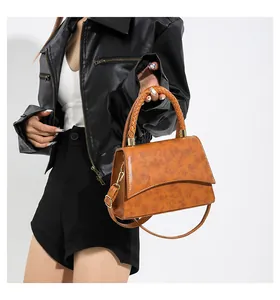 Détail de la poignée tressée et de la texture du sac à bandoulière marron en similicuir