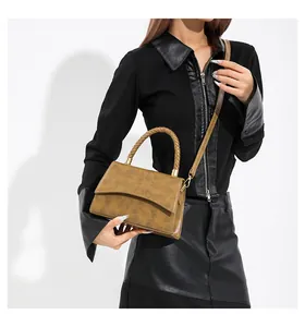Détail d'un sac à main marron vintage gaufré avec poignée tressée et finitions dorées porté