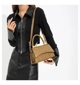 Gros plan sur un sac à main marron rétro avec poignée tressée et bandoulière amovible