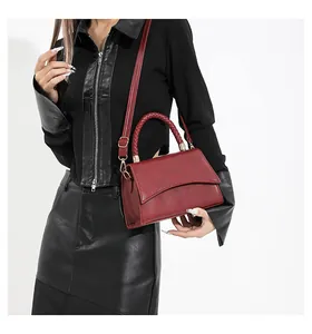 Détail du sac bordeaux texturé avec poignée tressée et garnitures en métal doré
