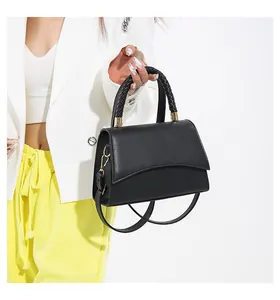 Détail d'un sac à main noir en similicuir avec poignée tressée et boucles en métal doré