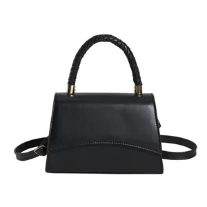 Sac à main noir en similicuir avec poignée tressée et détails dorés sur fond blanc