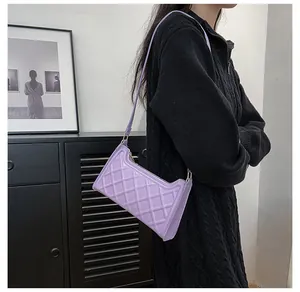 Dettaglio della borsa a tracolla trapuntata viola con finitura lucida e fibbie dorate