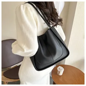 Close-up of a black leather tote bag with elegant arched stitching and slim shoulder straps