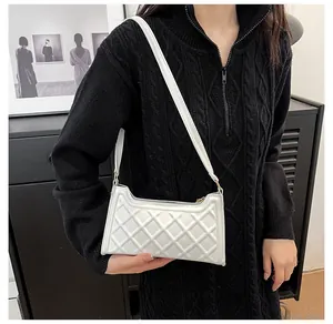 Dettaglio di una borsa sottobraccio in pelle PU bianca trapuntata su un maglione nero