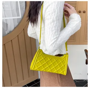 Dettaglio della borsa a spalla gialla trapuntata con cerniera indossata da una modella