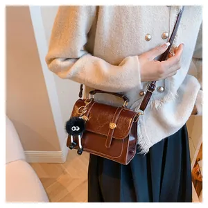 Borsa a tracolla vintage marrone con ciondolo in peluche indossata da una modella