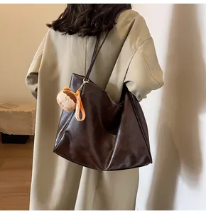 Dettaglio della grande borsa tote marrone scuro in ecopelle con ciondolo in peluche