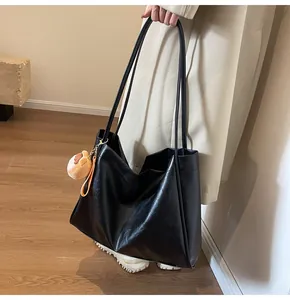 Dettaglio della borsa tote grande in pelle nera con tracolle e ciondolo a animale