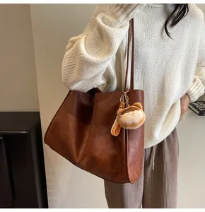 Borsa tote marrone in pelle sintetica con ciondolo di peluche mostrata di profilo