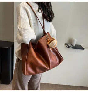Dettaglio della grande borsa tote marrone vintage con ciondolo a orsetto su pelle morbida
