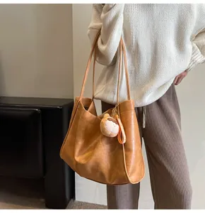 Grande borsa tote marrone con ciondolo a forma di orso indossata da una modella