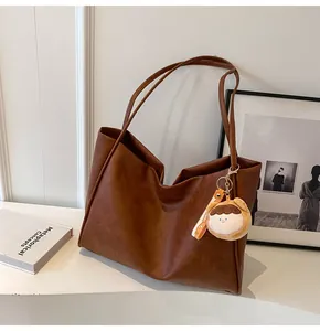 Dettaglio borsa shopper marrone in pelle martellata con ciondolo a bambola di peluche