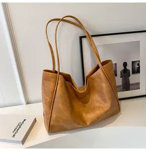 Dettaglio borsa tote in pelle marrone vintage con texture morbida e spalline