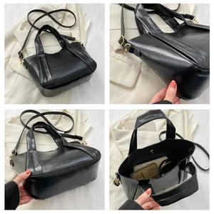 Vista detallada del bolso tipo cubo de cuero PU negro con herrajes dorados y asa