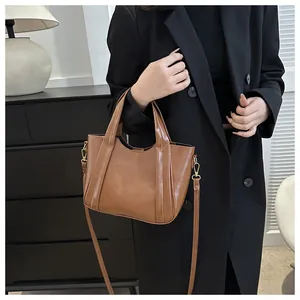Detail of brown faux leather handbag with adjustable gold hardware strap on model