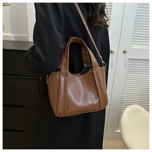 Detailed view of brown faux leather bucket bag with wide handles and glossy finish