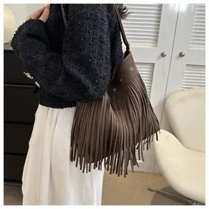 Detailed view of dark brown suede shoulder bag with long fringes and metal eyelets