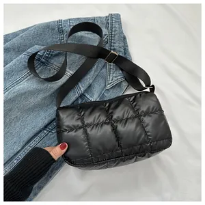 Détail du sac bandoulière matelassé noir avec sangle réglable sur fond en jean bleu