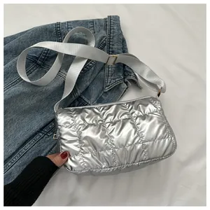 Détail d'un sac à bandoulière matelassé argenté avec une large sangle en tissu réglable