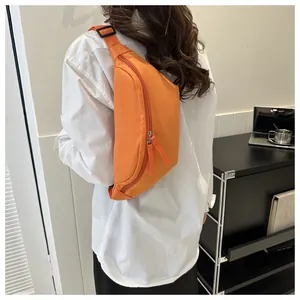 Detail of bright orange nylon crossbody bag showing dual zippers and adjustable strap