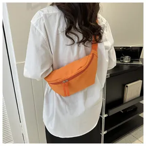 Detail of bright orange nylon crescent fanny pack with dual zippers and woven strap