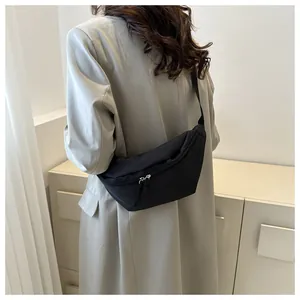 Rear view of minimalist black nylon crossbody bag with adjustable strap and double zippers
