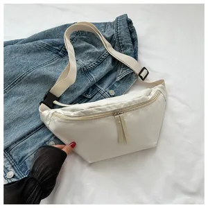 Detail showing white canvas crossbody bag with adjustable strap and double zipper hardware