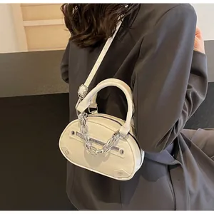 White mini crescent bag with silver chain detail shown as a crossbody on a model