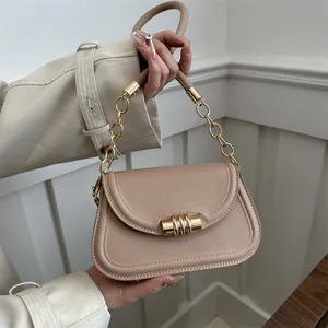 Minimalist beige crossbody bag with gold cylinder buckle and metal chain handle