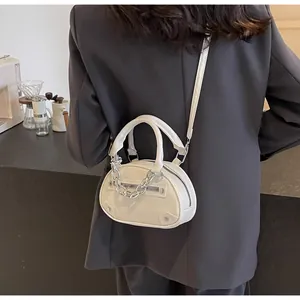 Detail of cream oval PU handbag featuring chunky silver chain and rivet accents