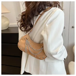 Détail du sac sous le bras marron clair avec chaînes argentées et rivets sur blazer