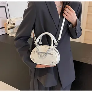 Close-up of a white leather crossbody bag featuring bold silver chains and zippers