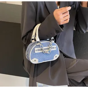 Detail of denim and white leather bag with silver chain and functional small zipper