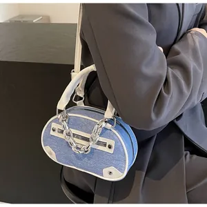 Detail of blue denim crossbody bag with white leather trim and chunky metal chain strap