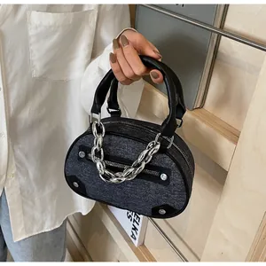 Detailed close-up of dark grey denim tote with black leather handle and silver metal chain