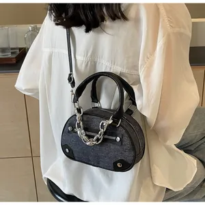 Detailed view of gray denim Boston bag with silver chain and black leather handles