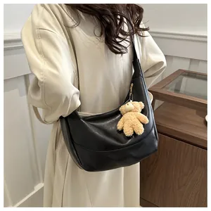 Detailed shot of large black soft leather hobo bag with cute plush bear charm decoration