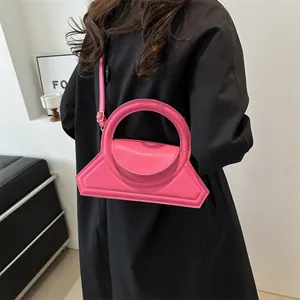 Hot pink leather handbag with geometric design and shoulder strap worn by model